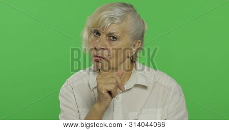 An Elderly Woman Quarrels At Someone. Old Unkind Grandmother Scolding In A White Shirt. Place For Yo