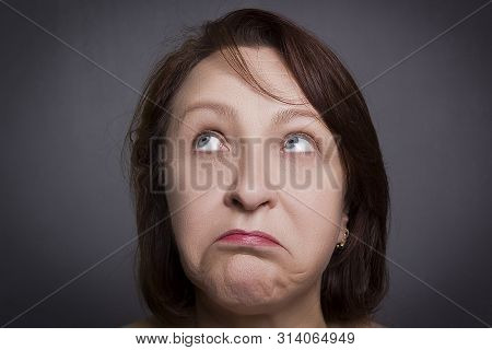 Woman Grimaces In Front Of Camera On Black Background