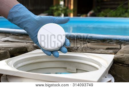Female Hand Puts White Tablets Into Pool Skimmer. Cleaning, Disinfection Of Water In The Swimming Po