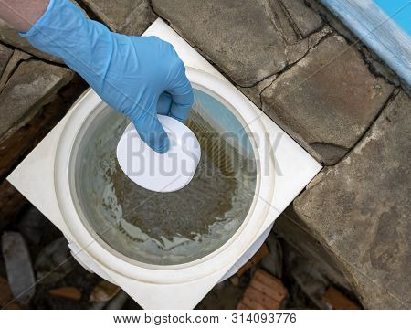 Female Hand Puts White Tablets Into Pool Skimmer. Cleaning, Disinfection Of Water In The Swimming Po