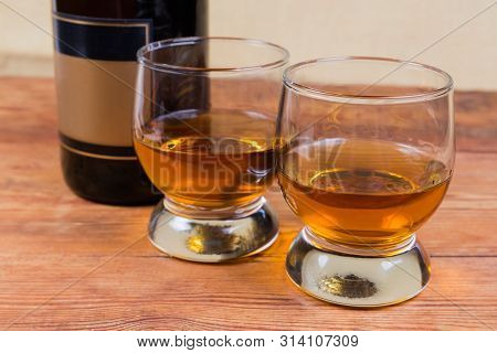 Two Portions Of Brandy In Brandy Bowls On A Background Of Brandy Bottle On The Rustic Table In Selec
