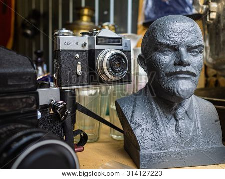 Krasnodar, Russia - July 5, 2019: Sculpture Of Vladimir Lenin. Old Soviet Camera Zenit-e. Antiques M