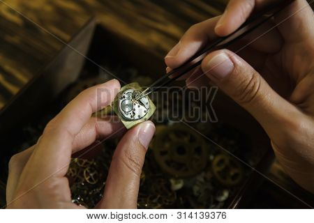 Girl Craftsman Dismantles Clock. Repairing Vintage Watches. Female Hands Holding Tweezers. Disassemb