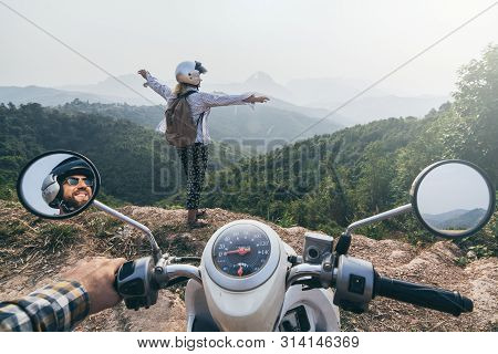 Young Caucasian Couple Riding A Motorcycle In Laotian Mountains. Woman Standing On Cliff Edge, Hands