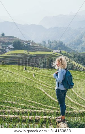 Young Caucasian Blonde Woman In Denim Shirt Overlooking Sapa Rice Terraces At Sunset In Lao Cai Prov