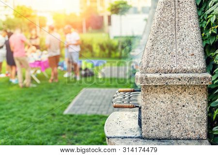 Outdoor Stone Stove With Grill And Skewers. Company Of Friends At Barbecue Party At Park Or Backyard