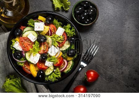 Greek Salad. Vegetable Salad From Tomato, Cucumber, Feta Cheese And Olive Oil On Black Stone Table. 