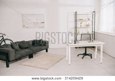 Spacious Living Room With Grey Sofa, White Table And Rack With Books