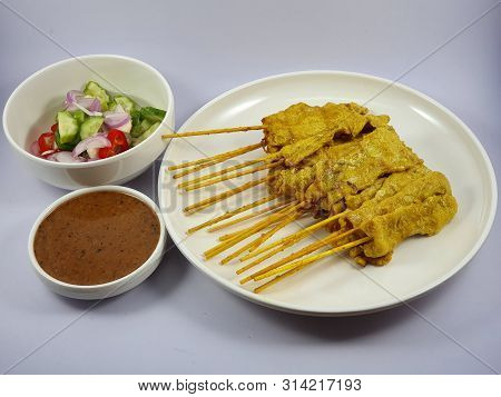 Pork Satay kebab with some vegetables and sauce.