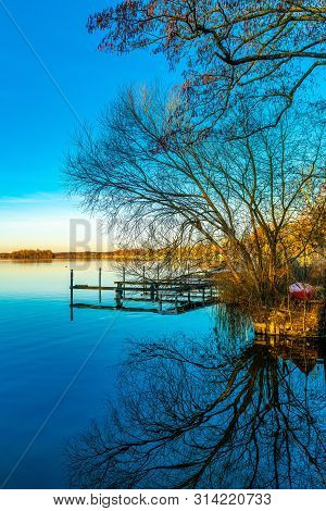 High Size Picture Of A Landing Stage And Trees At A River Bank With Gorgeous Reflections In The Wate
