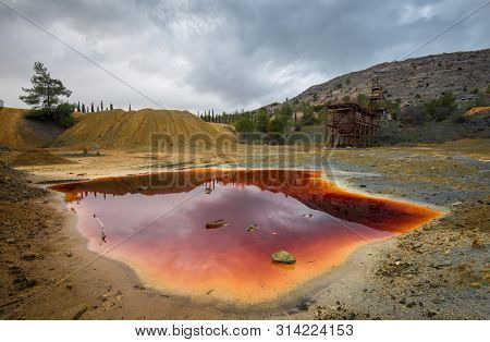 Abandoned Copper Mine With Red Toxic Water And Dramatic Stormy Cloudy Sky At Mitsero Area In Cyprus