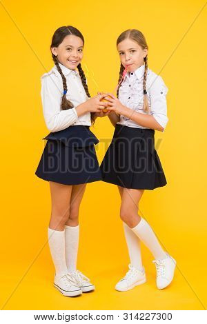 Feeling Healthy Is Wonderful. Thirsty School Girls On Yellow Background. Little Girls Drinking Juice