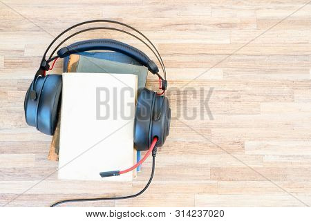 Audio Book Concept. Headphones And Pile Of Books On Wooden Table. Top View With Copy Space.