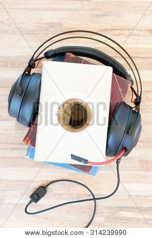 Audio Book Concept. Black Headphones With Books And Cup Of Black Coffee On Wooden Table. Top View