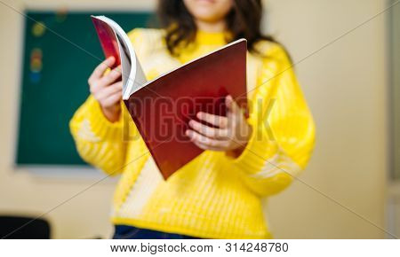 Portrait Of Cute Girl Reading Book In Classroom. Educational Process.