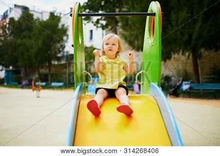 Adorable Toddler Girl On Playground Slide. Outdoor Activities For Kids