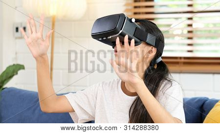 Young Asian Woman Exciting In Vr Headset Looking Up And Trying To Touch Objects In Virtual Reality A