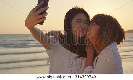 Young Asian Lesbian Couple Using Smartphone Taking Selfie Near Beach. Beautiful Women Lgbt Couple Ha