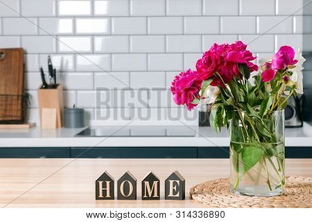 Beautiful Pink Peonies In A Glass Vase Standing On The Kithcen With White Brick Tile Wall.