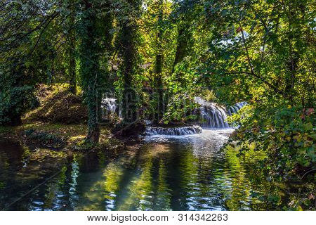  Small waterfalls on the Korana River. Magnificent forests surround the city and the river. Travel to Croatia. Wonderful  day. The town of Slunj. The concept of ecological, active and photo tourism