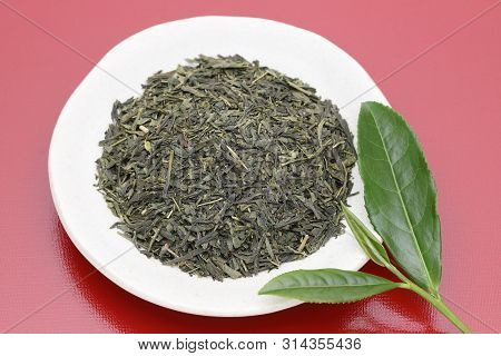 Dried Tea Leaves With Green Tea Leaves On Red Background