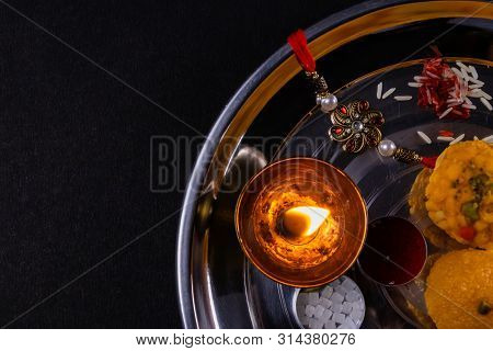 Indian Festival Of Brothers And Sisters - Rice Grains, Kumkum, Sweets And Diya On Plate With An Eleg