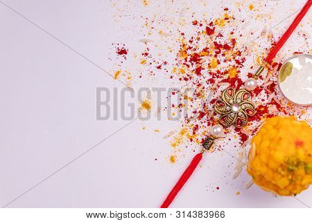 Raksha Bandhan Background - Elegant Rakhi, Sweets And Cardamom With Sugar Crystal Rock In A Flat Rou