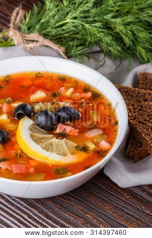 Traditional Russian Meat Soup Solyanka In Bowl On Rustic Wooden Table
