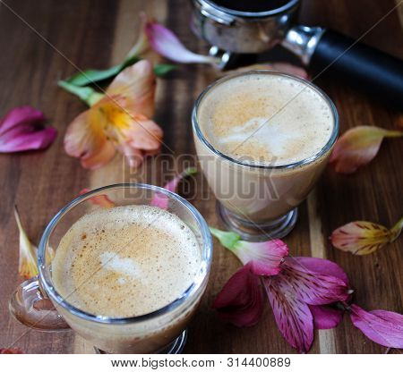 Two Coffees With Milk Surrounded By Flower Petals