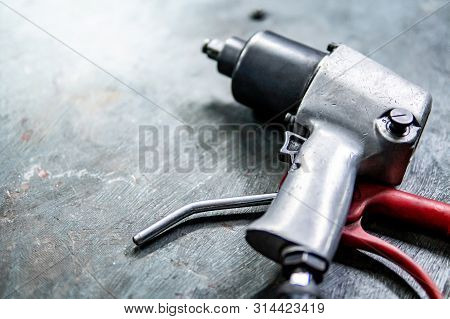 Pneumatic Wrench On Concrete Floor In Auto Repair Shop. Car Wheel Repairing Concept