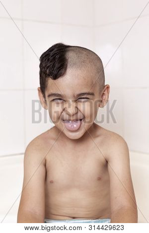 Six-year Boy At Haircutting At Home. Father Cut Half Of The Son's Hair Off At The Bathroom