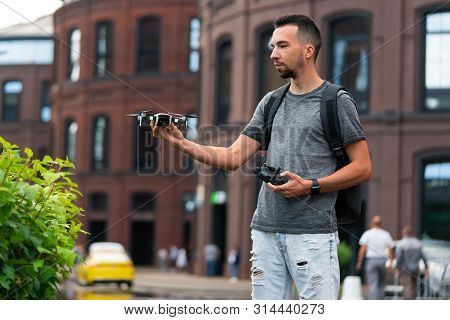 Young Handsome Man Launching Drone Quadcopter At Urban Background.