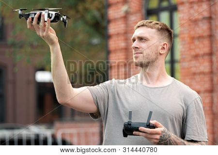 Young Handsome Man Launching Drone Quadcopter At Urban Background.