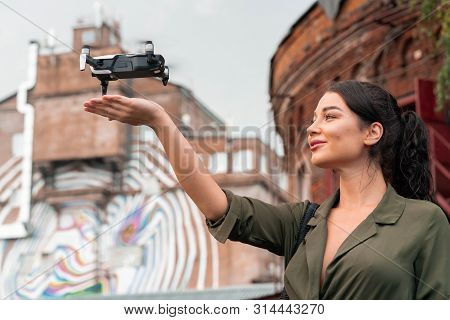 Young Beautiful Woman Launching Drone Quadcopter At Urban Background.