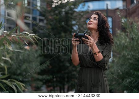 Young Beautiful Woman Launching Drone Quadcopter At Urban Background.