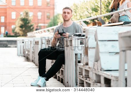 Young Handsome Man With Drone Quadcopter Joystick Controller At Urban Background.