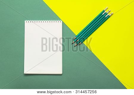 White Wideopen Blank Clean Notepad Page And Green Pencils On Yellow-green Table.