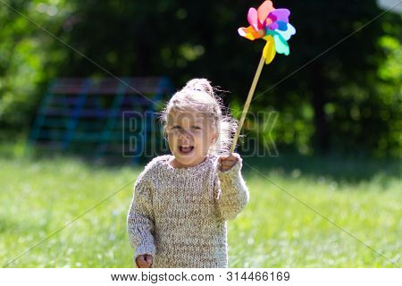 Child With Pinwheel In The Summer Park Looking At Camera