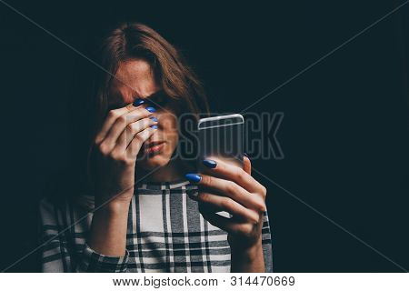 Sad Teen Being Victim Of Cyber Bullying Online Sitting On A Couch In The Living Room At
