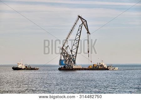 Towed Floating Crane On Water Agains Sky