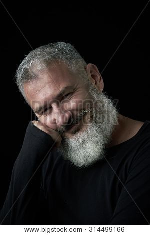 Portrait Of A Smiling Brutal Gray-haired Man With A Gray-haired Lush Beard On A Black Background, Se