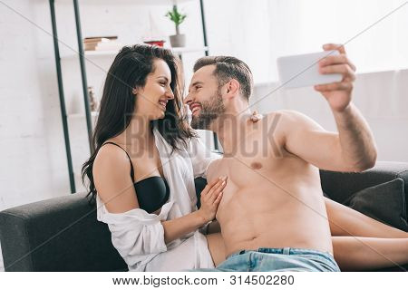 Handsome Man And Sexy Woman In Shirt And Bra Looking At Each Other And Taking Selfie