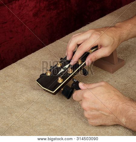 Musical Instrument Guitar Repair And Service - Worker Fix New Strings Black Acoustic Guitar