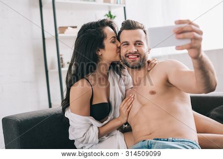 Handsome Man And Sexy Woman In Shirt And Bra Kissing And Taking Selfie