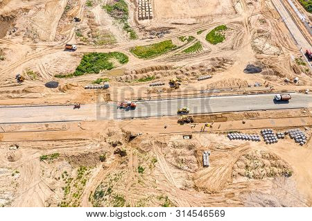 Industrial Roadrollers And Dump Trucks Doing Earthwork At Construction Site. Top View