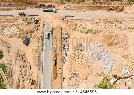 Aerial Top View Of Construction Site. Roadrollers, Excavators And Dump Trucks Prepare Ground For Roa