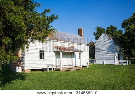 Surry, Virginia/usa - July 20, 2019: A Preserved 1830s Slave Cabin With One Of Many Other Outbuildin