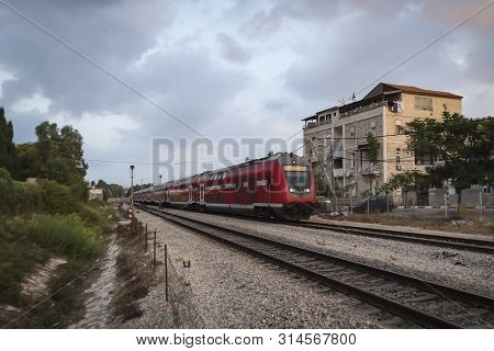 Modern High Speed Train On A Cloudy Day Moving In Suburbs. Railway System In Israel. Suburban Train 