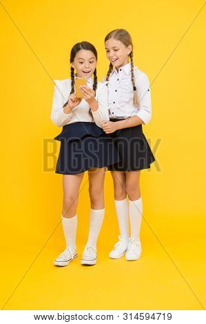 Girls School Uniform Using Smartphone. Schoolgirls Use Mobile Phone Or Smartphone To Share Photos. S