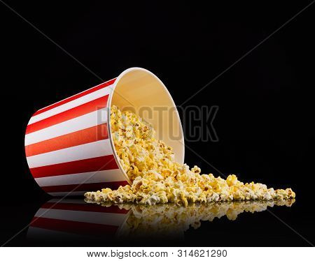 Scattered Popcorn From Paper Striped Bucket Isolated On Black Background